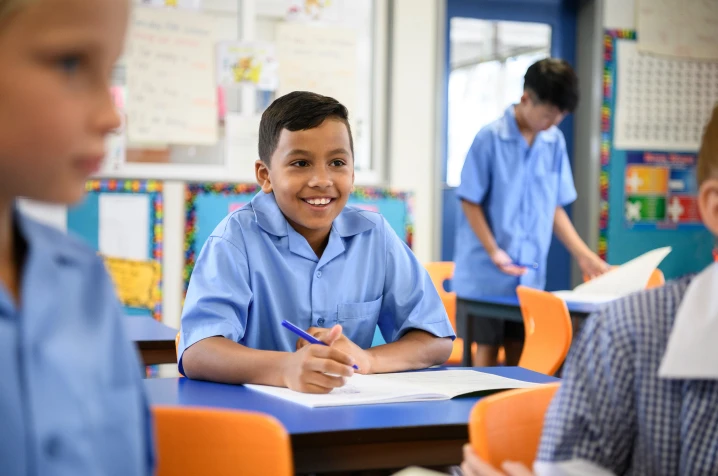 Child sitting in classroom smiling.