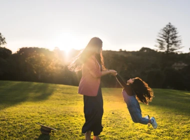 Woman playing with her daughter in a sunny park.