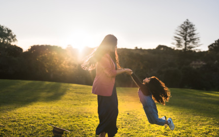 Woman playing with her daughter in a sunny park.