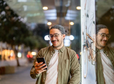 Man standing by window holding a phone and smiling