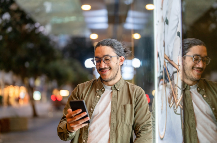 Man standing by window holding a phone and smiling