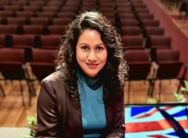 Shristi looking at the camera in a theater holding her certificate of NZ citizenship.
