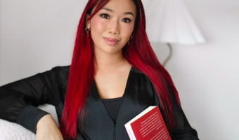 Sophia looking at the camera holding a book.