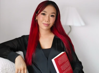 Sophia looking at the camera holding a book.