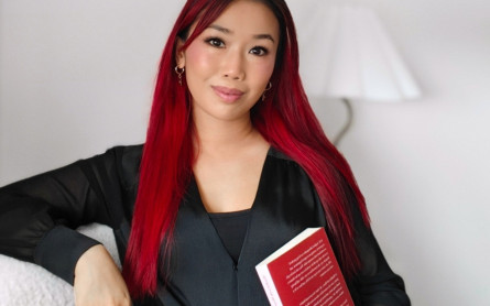 Sophia looking at the camera holding a book.