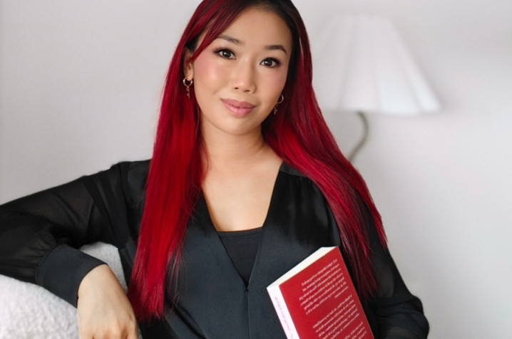 Sophia looking at the camera holding a book.