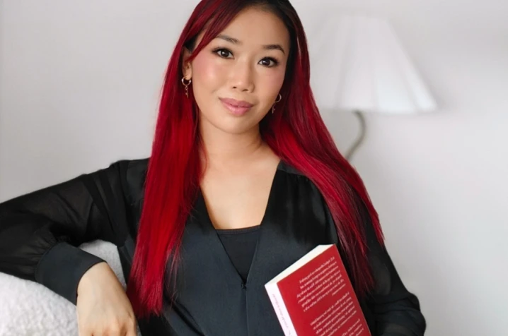 Sophia looking at the camera holding a book.