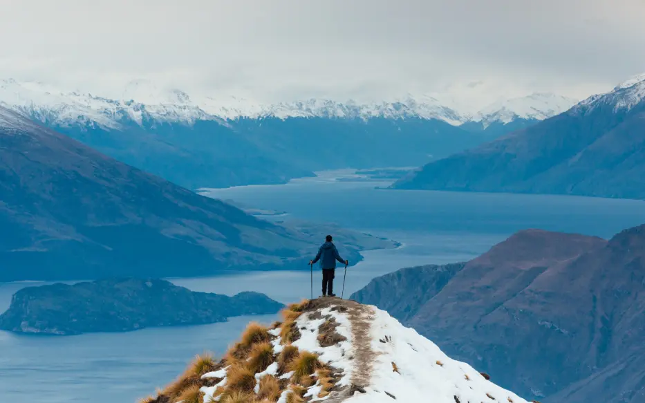 Person standing at the top of a mountain with lakes view.