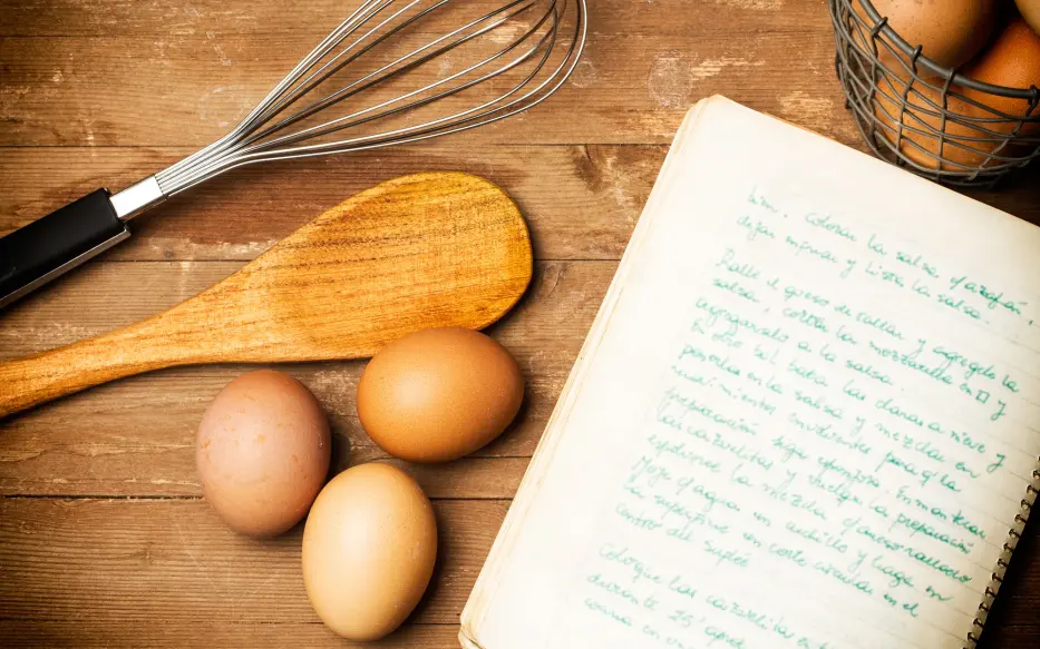 Cooking utensils, three eggs and a notebook.