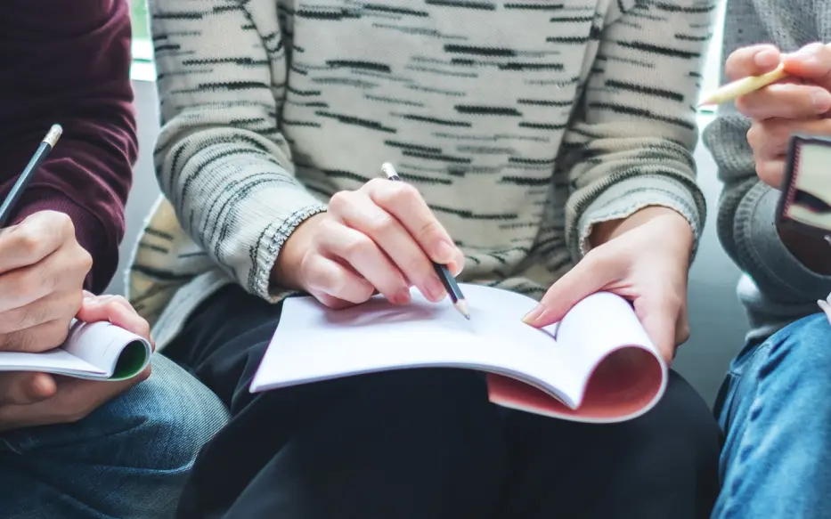 Close up of woman holding a notebook and a pencil