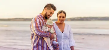 Couple holding a baby on the beach.